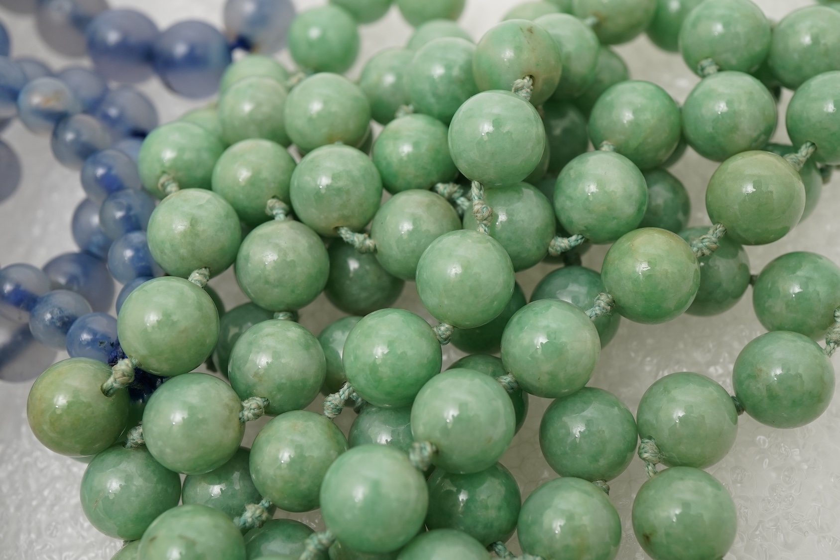 A Chinese jade ‘spirit lock’ plaque, a jadeite bead necklace and a blue quartz bead necklace, 20th century